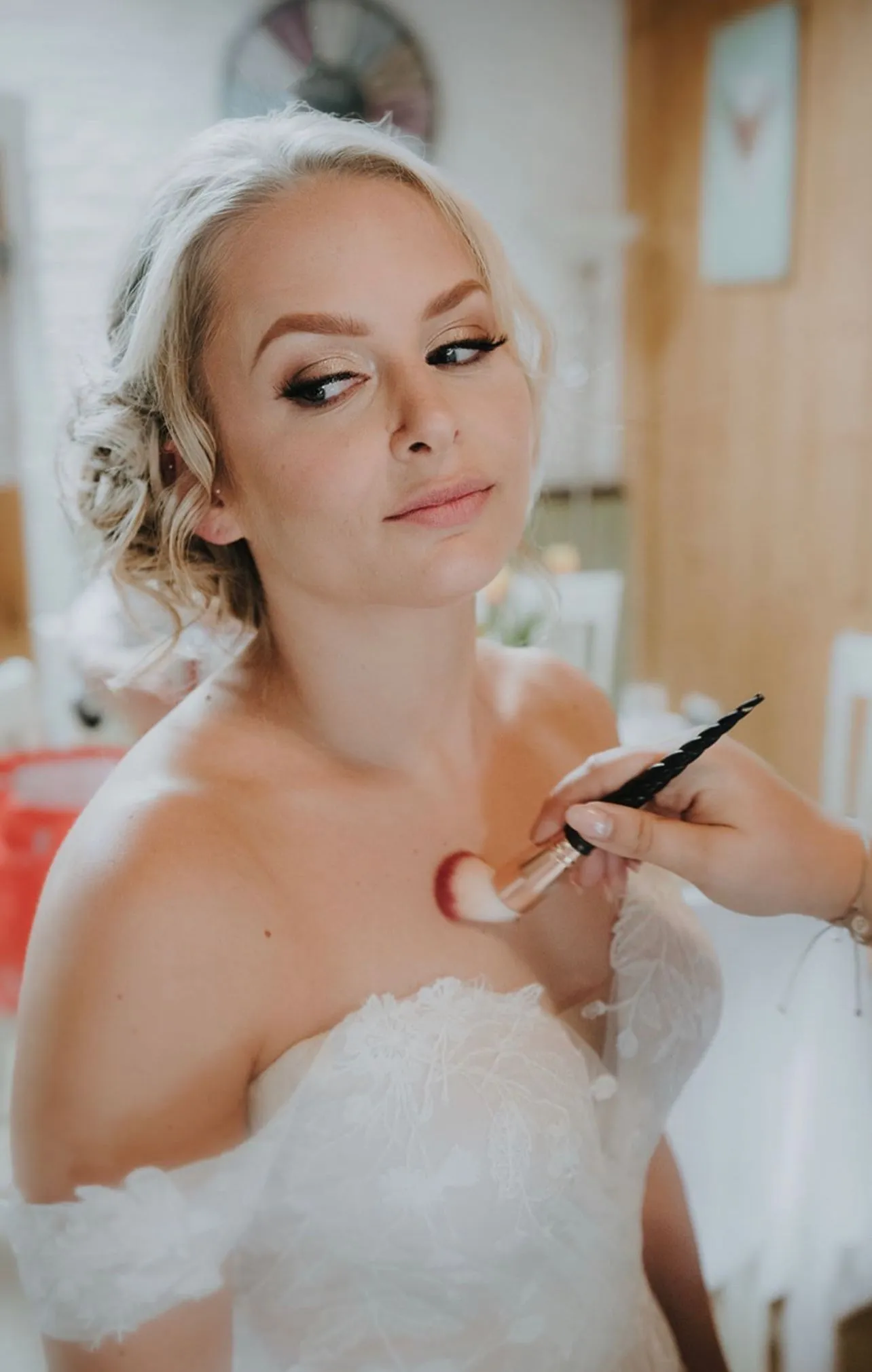 Bride in a lace wedding dress having her makeup finished during a Roselli & Co. bridal booking